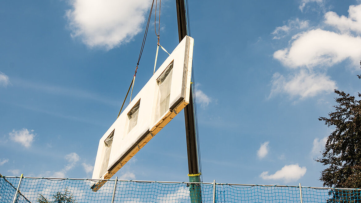 Modulbauwand mit GFK Fassadenplatte am Kran hängend