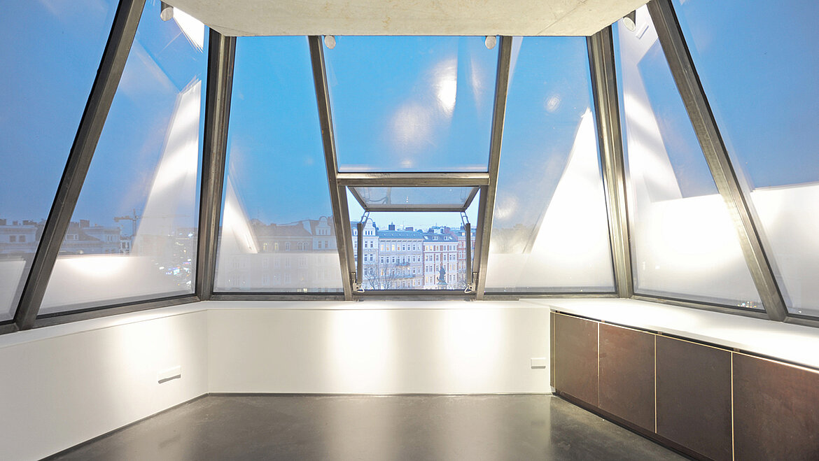 Ein lichtdurchflutetes Dachgeschoss mit großen Glaselementen und einem geöffneten Fenster.