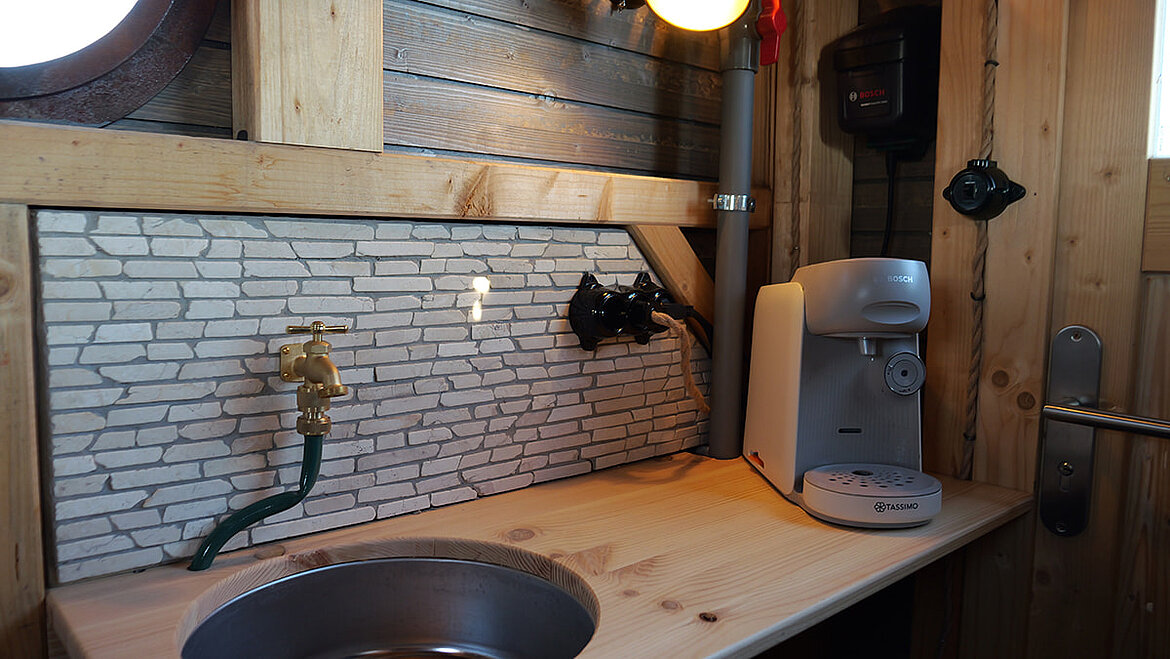 Innenraum des Leuchtturms mit Holzarbeitsplatte, Spüle, Wasserhahn und Kaffeemaschine