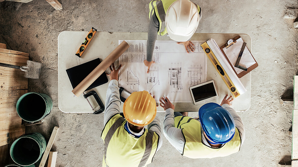Architekten besprechen Baupläne an einem Holztisch
