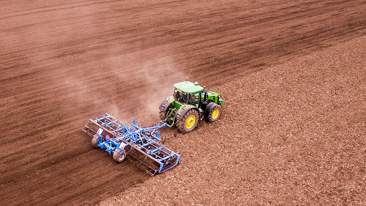 Traktor mit Pflug bearbeitet Ackerfläche