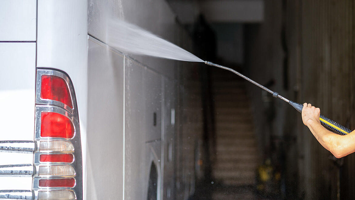 Reinigung einer Busseitenwand mit einem Dampfstrahler Mann mit Dampfstrahler wäscht Busseitenwand | insights by LAMILUX