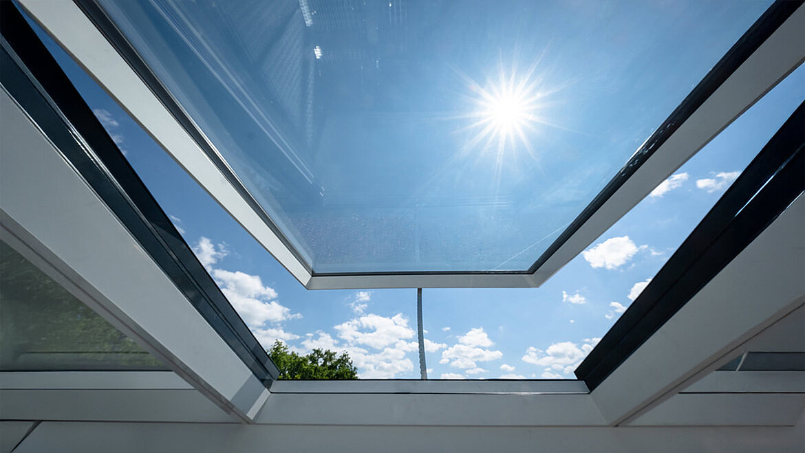 Wohnhaus in Freiburg mit modularen Glasdach von LAMILUX, Blick durch das geöffnete Dach in den Himmel.