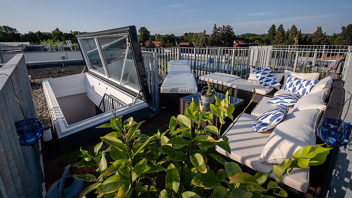 Moderne Dachterrasse mit geöffneten Glasaufbauten und Begrünung.