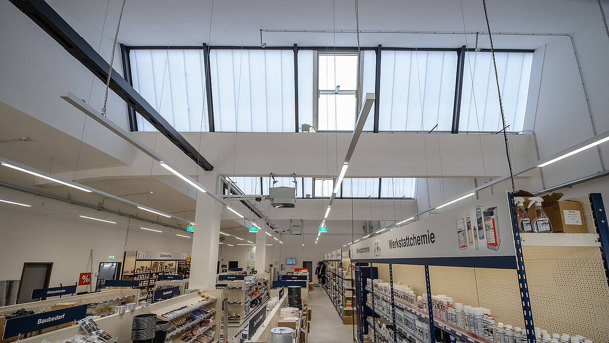 Modernisierter Innenbereich des alten Postbahnhofs Leipzig, jetzt genutzt als Fachmarkt mit Tageslichtsystemen und hohen Glasdachfenstern.