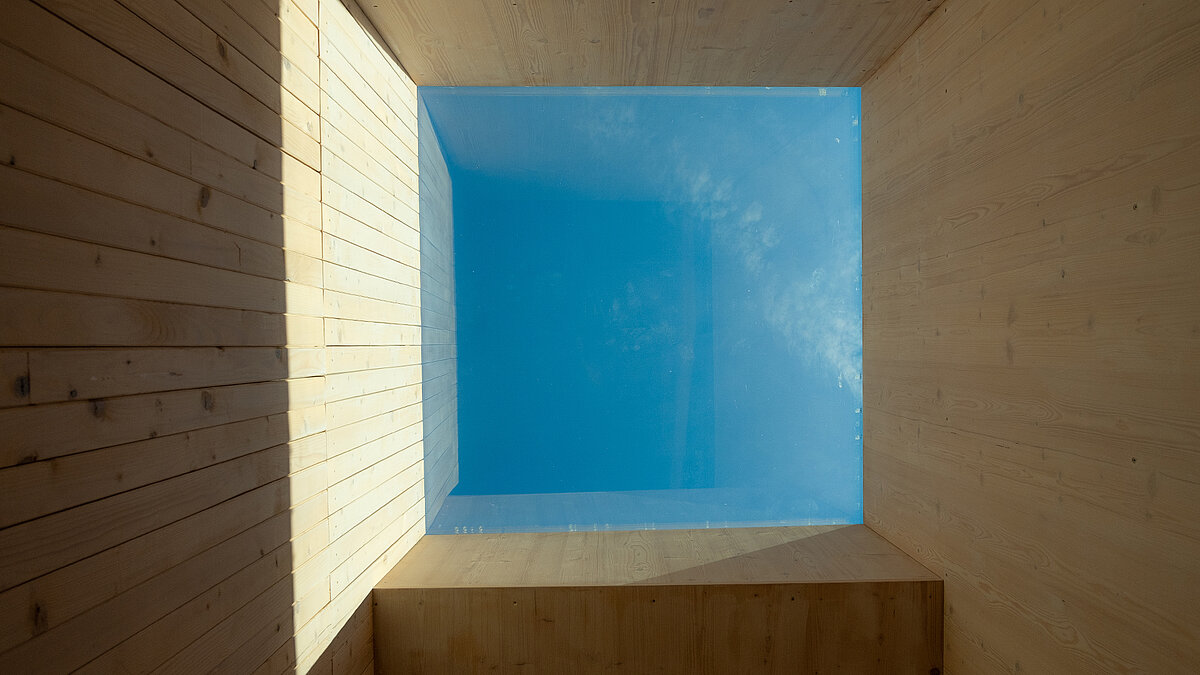 Oberlicht in der Kinderkrippe Waltenhofen, das durch ein rechteckiges Dachfenster Tageslicht auf die holzverkleideten Wände wirft.