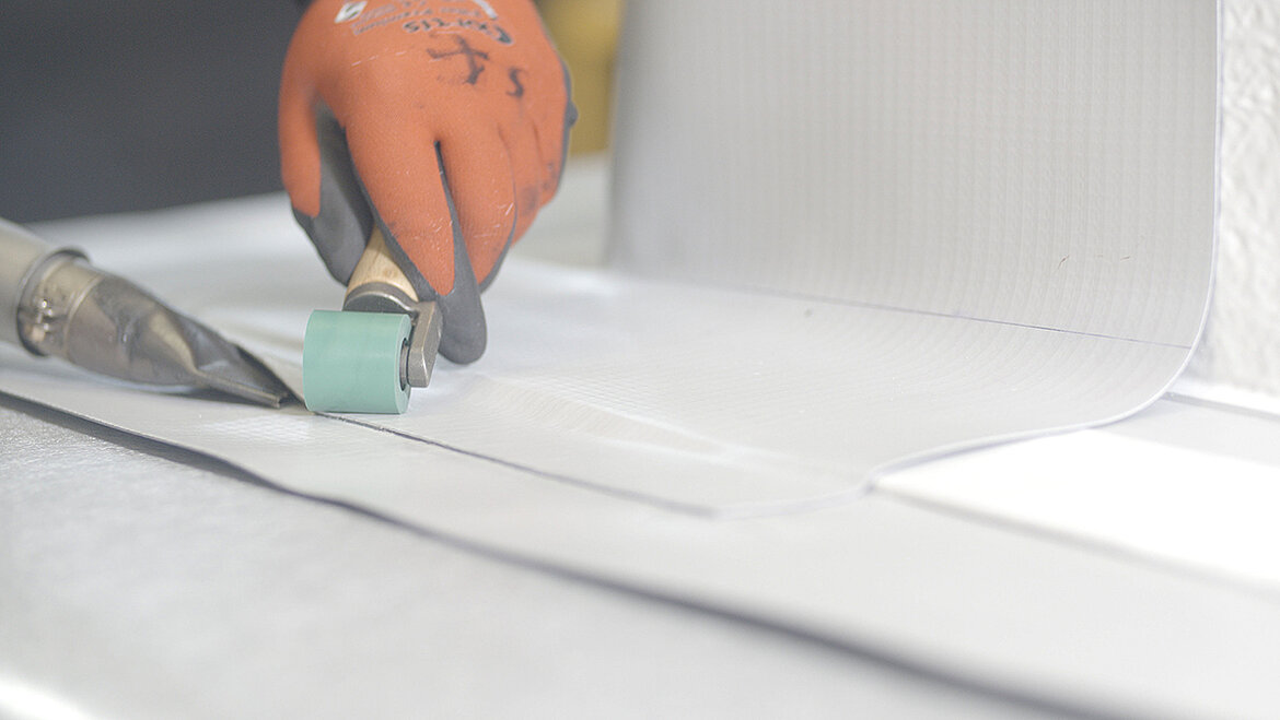 Detailaufnahme einer Aufsatzkranzabdichtung mit verschweißter Dachbahn am Flachdach