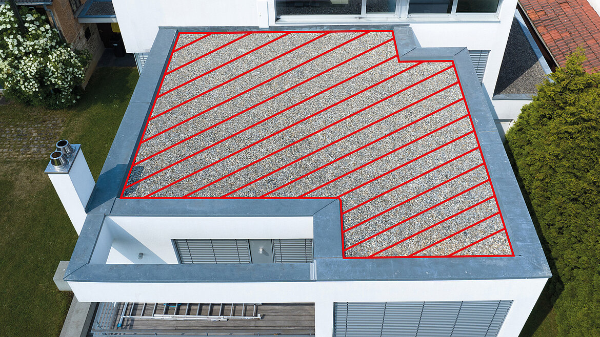 Flachdach eines modernen Hauses mit Kiesbelag und rot markierter Fläche.