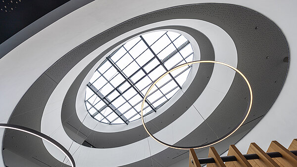 Blick nach oben auf das LAMILUX  Glasdach im Kompetenzzentrum Breisgau mit moderner Ringbeleuchtung und architektonischem Atrium.