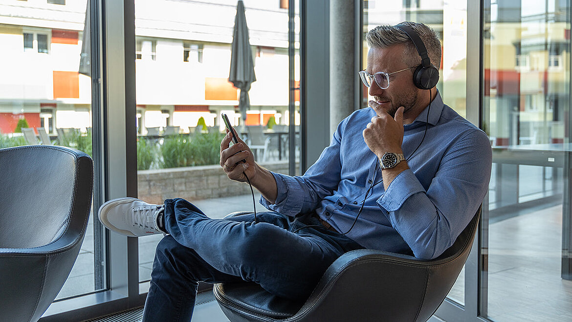 Mann hört einen Podcast übers Handy 