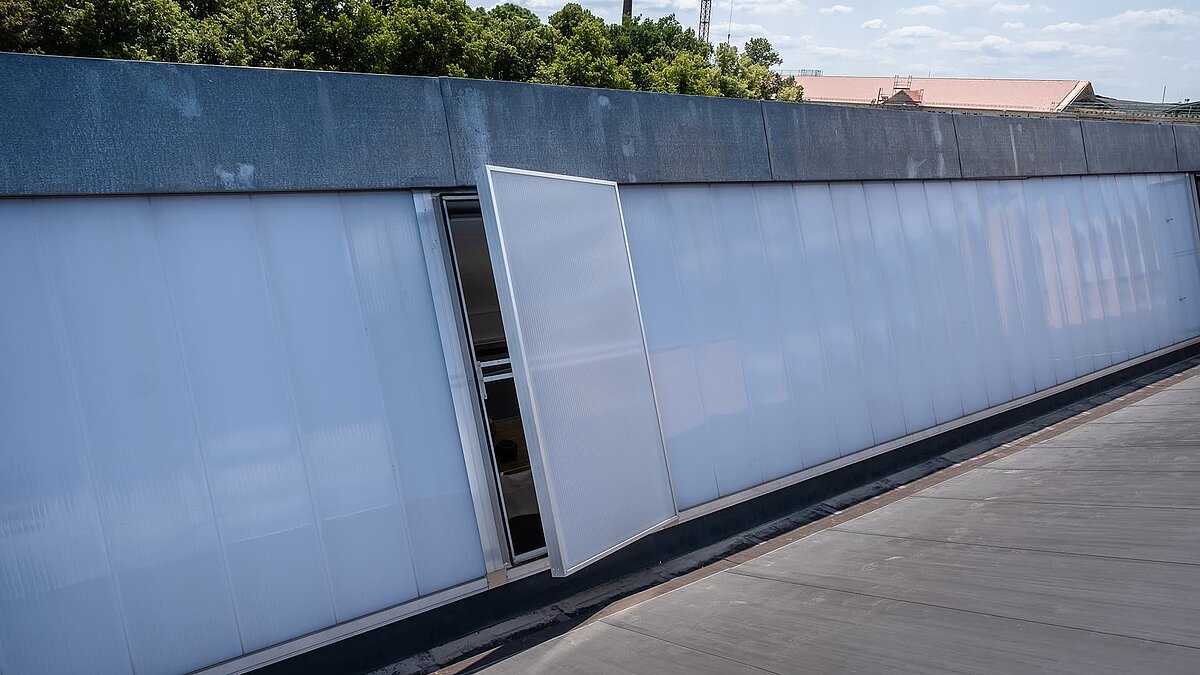 Detailansicht des Dachs des alten Postbahnhofs Leipzig mit modernen Lichtbändern und geöffnetem Lüftungselement.