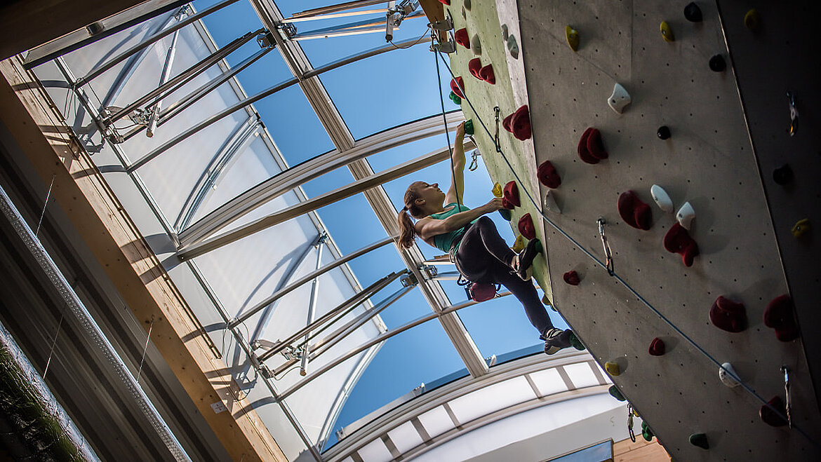 Blick auf eine Kletterin an der Kletterwand und im Hintergrund ein LAMILUX Lichtband