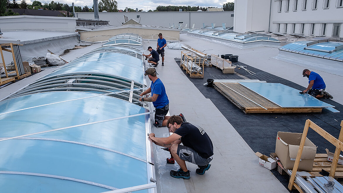 Arbeiter bei der energetischen Sanierung eines Flachdachs mit der Installation neuer Lichtbänder.