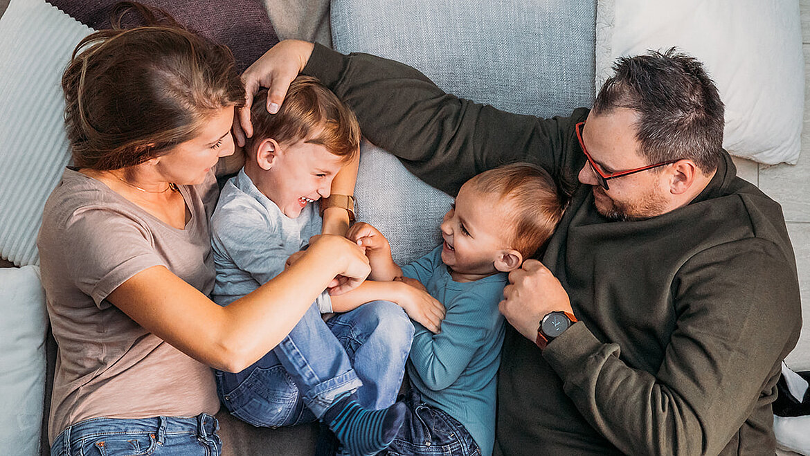Glückliche Familie kuschelt lachend auf dem Sofa