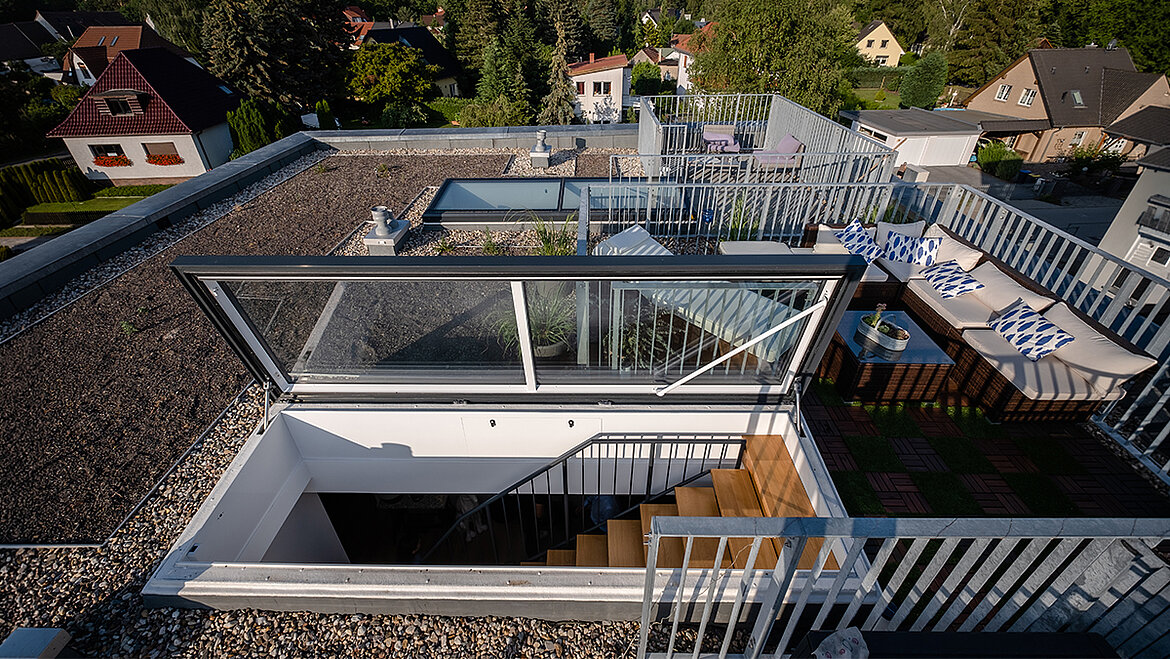 Moderne Dachterrasse mit Sitzbereichen und integriertem Glasdach auf einem Flachdach
