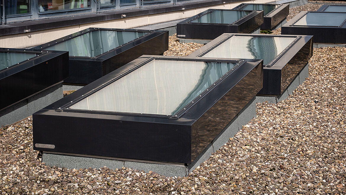 Mehrere Flachdachfenster auf einem Kiesdach mit Aufsatzkränzen im Außenbereich