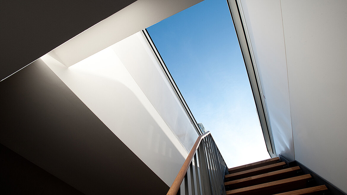 Treppe führt durch einen geöffneten Flachdach Ausstieg ins Freie mit Blick in den Himmel.
