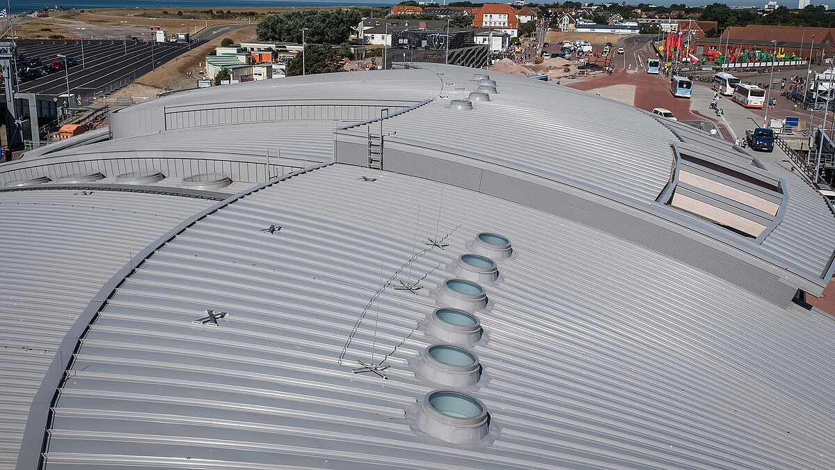 Dach des Hafenterminals Norderney mit runden Flachdach Fenstern und wellenförmiger Metallkonstruktion.