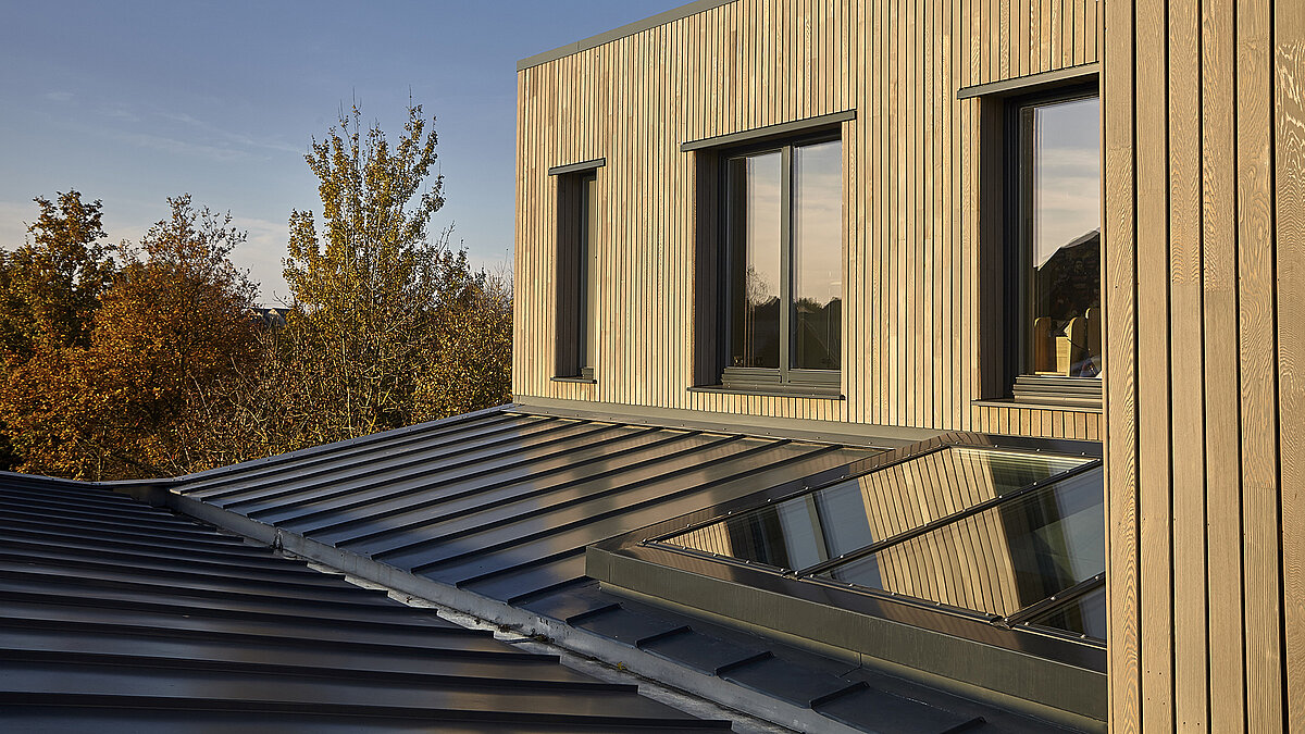 Modernes Gebäude der Potton Show Homes in England mit LAMILUX Glasdach PR60 und Holzfassade im warmen Abendlicht.