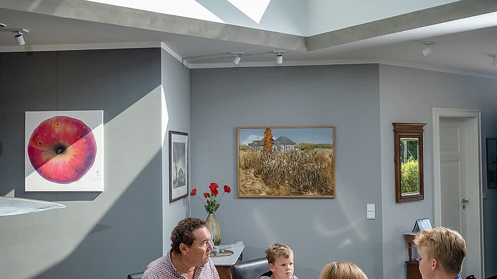 Familie beim Essen unter einer modernen Glaspyramide im Neubau eines Einfamilienhauses in Wichmannsdorf.
