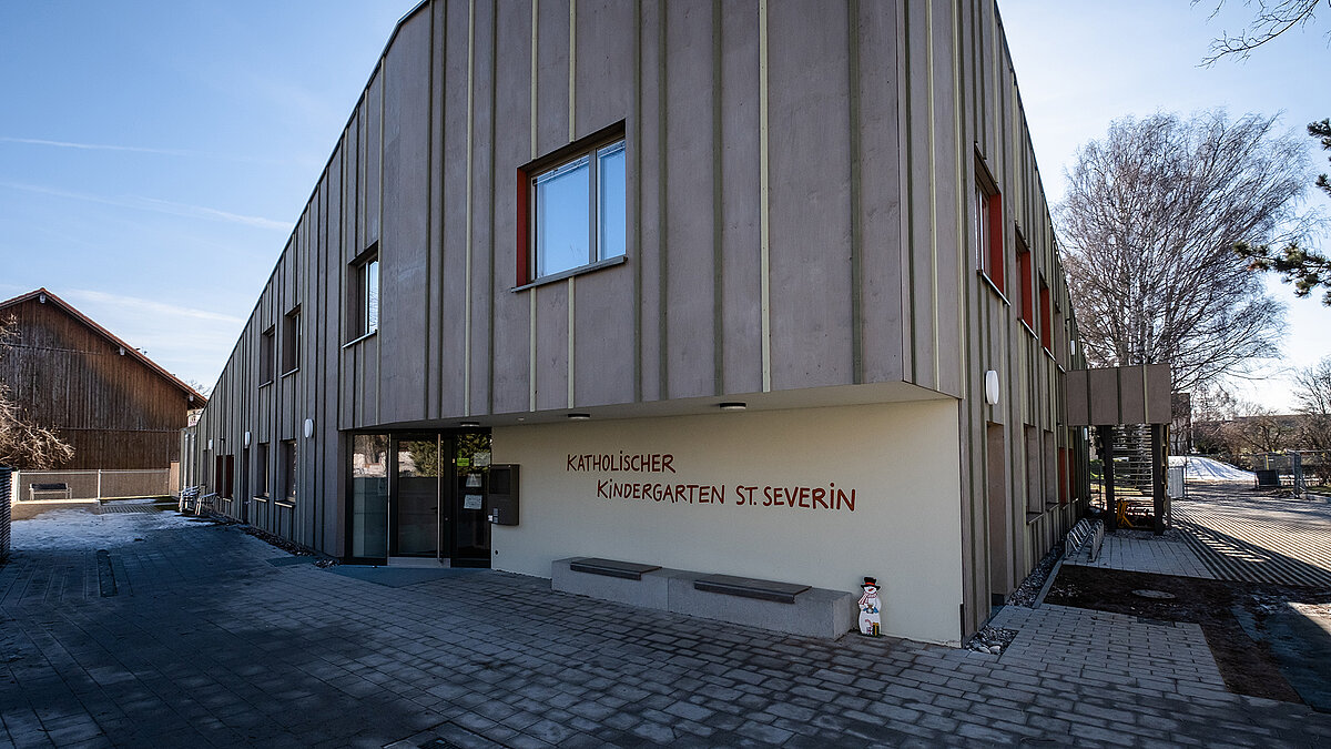Außenansicht des Kindergartens St. Severin mit moderner Holzfassade und großen Fenstern.