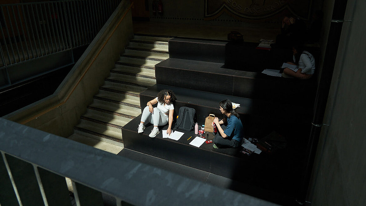 Zwei Personen sitzen im Sonnenlicht und arbeiten mit Laptops