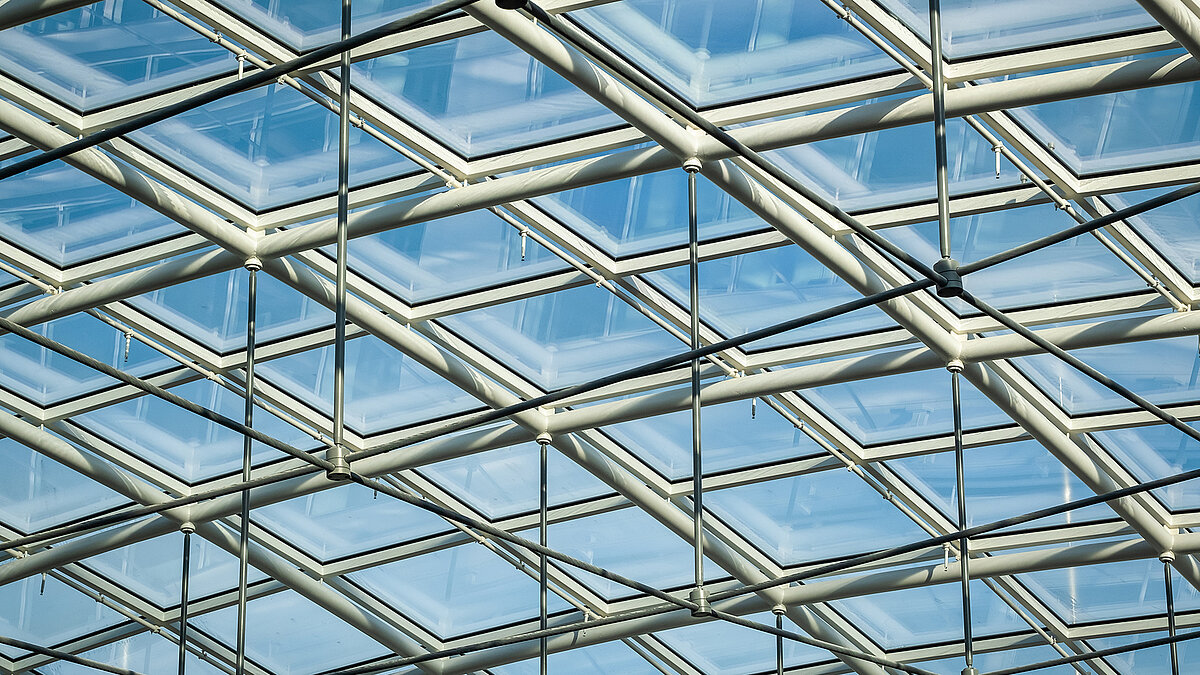Glasdach des Bürogebäudes Newton der TÜV Süd Gruppe mit Metallträgern und blauem Himmel im Hintergrund.