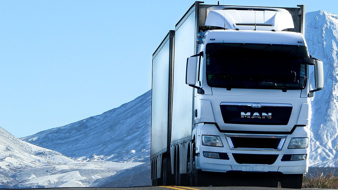 Weißer LKW vor verschneiter Berglandschaft