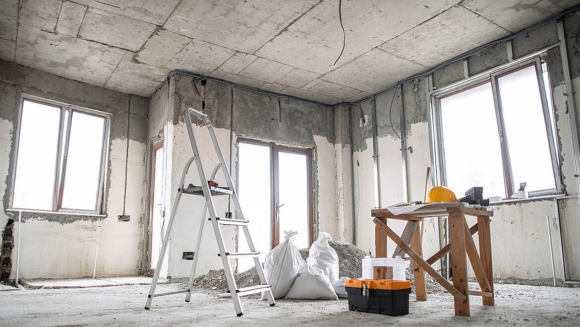 Gebäude im Rohbau mit Werkzeugen, Leiter und Baumaterialien für Renovierungsarbeiten