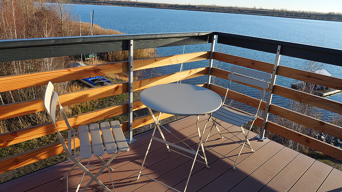 Gemütliche Terrasse des DIY-Leuchtturms, mit Holzgeländer und Blick auf einen See