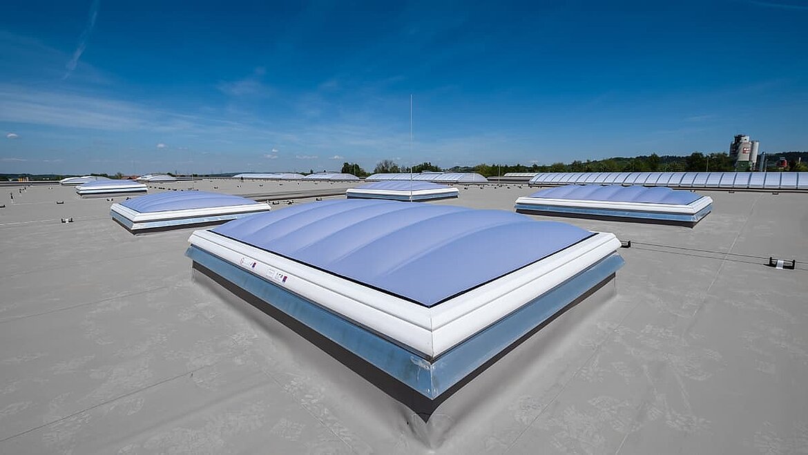 Lamilux Flachdach mit mehreren Lichtkuppeln unter blauem Himmel.