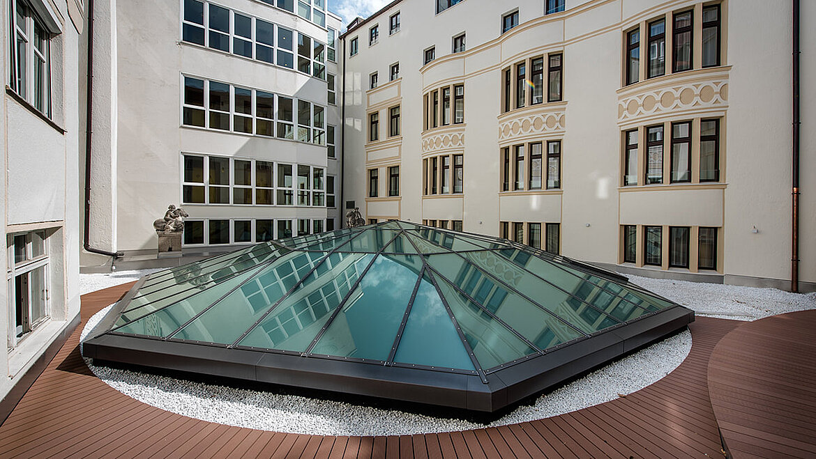 Glaspyramide mit Lüftungsflügel auf dem Lobbydach des Hotels Vier Jahreszeiten in München Individuell gestaltete Glasdachpyramide LAMILUX PR60 zwischen Hotelgebäuden | insights by LAMILUX