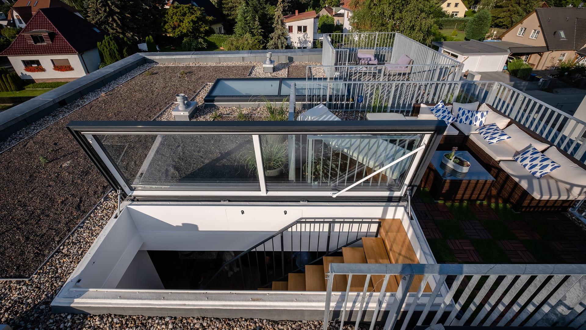 Flachdach-Ausstieg auf moderne Dachterrasse mit Pflanzen und Sitzmöbeln